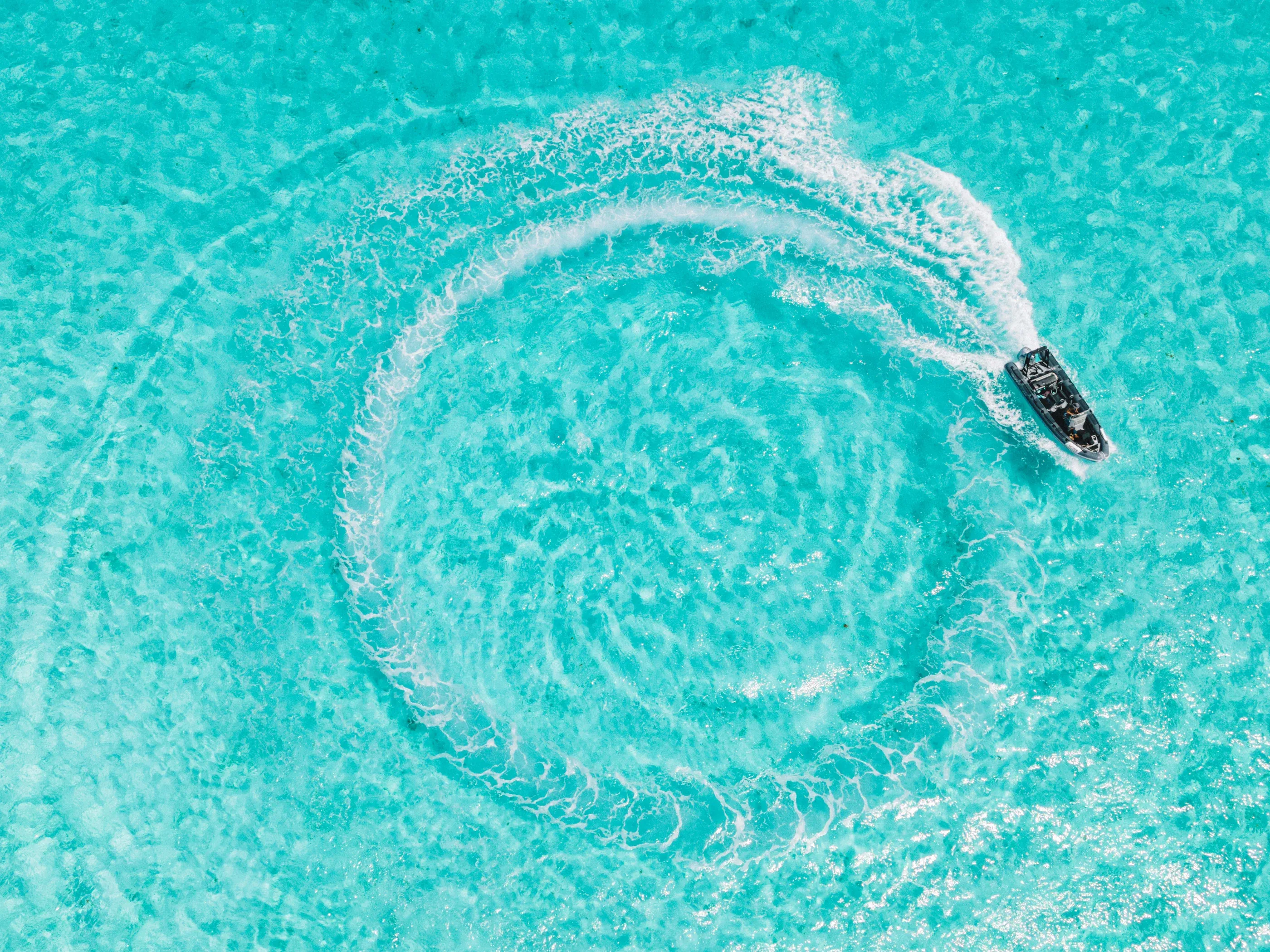 The boat carving a circle in the turquoise shallows, from above