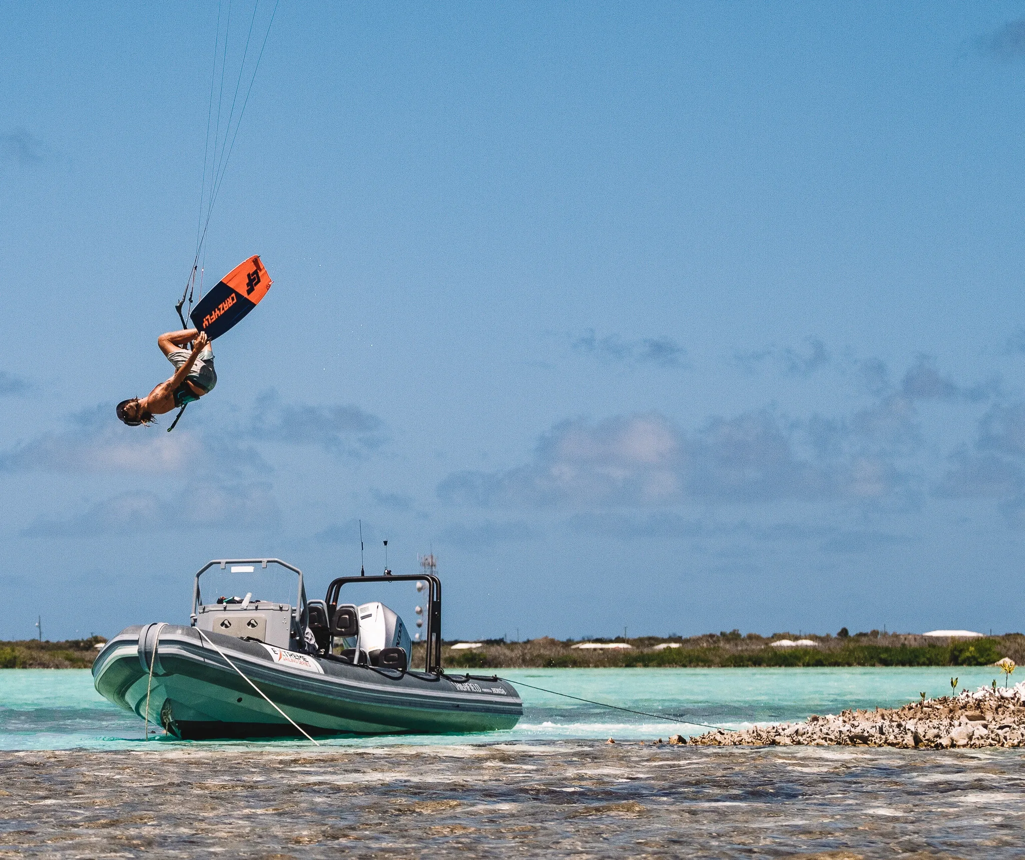 A kiter flipping high above the RIB, anchored in the shallows by the conch shell mounds